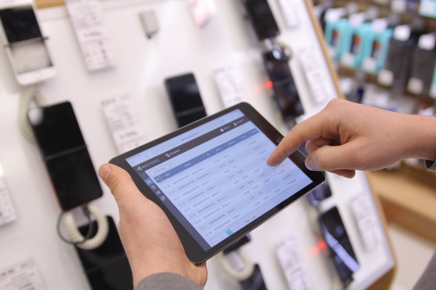 Hands managing retail inventory on a tablet screen.
