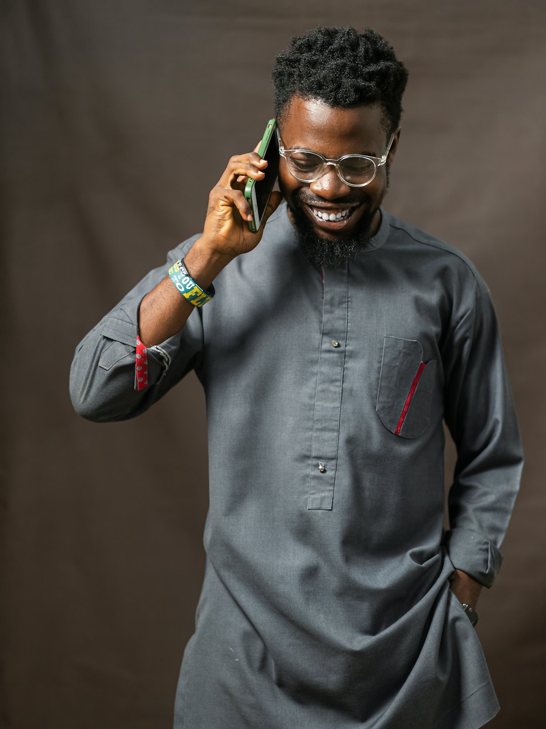 Young Black man laughs during a phone call on a green smartphone.