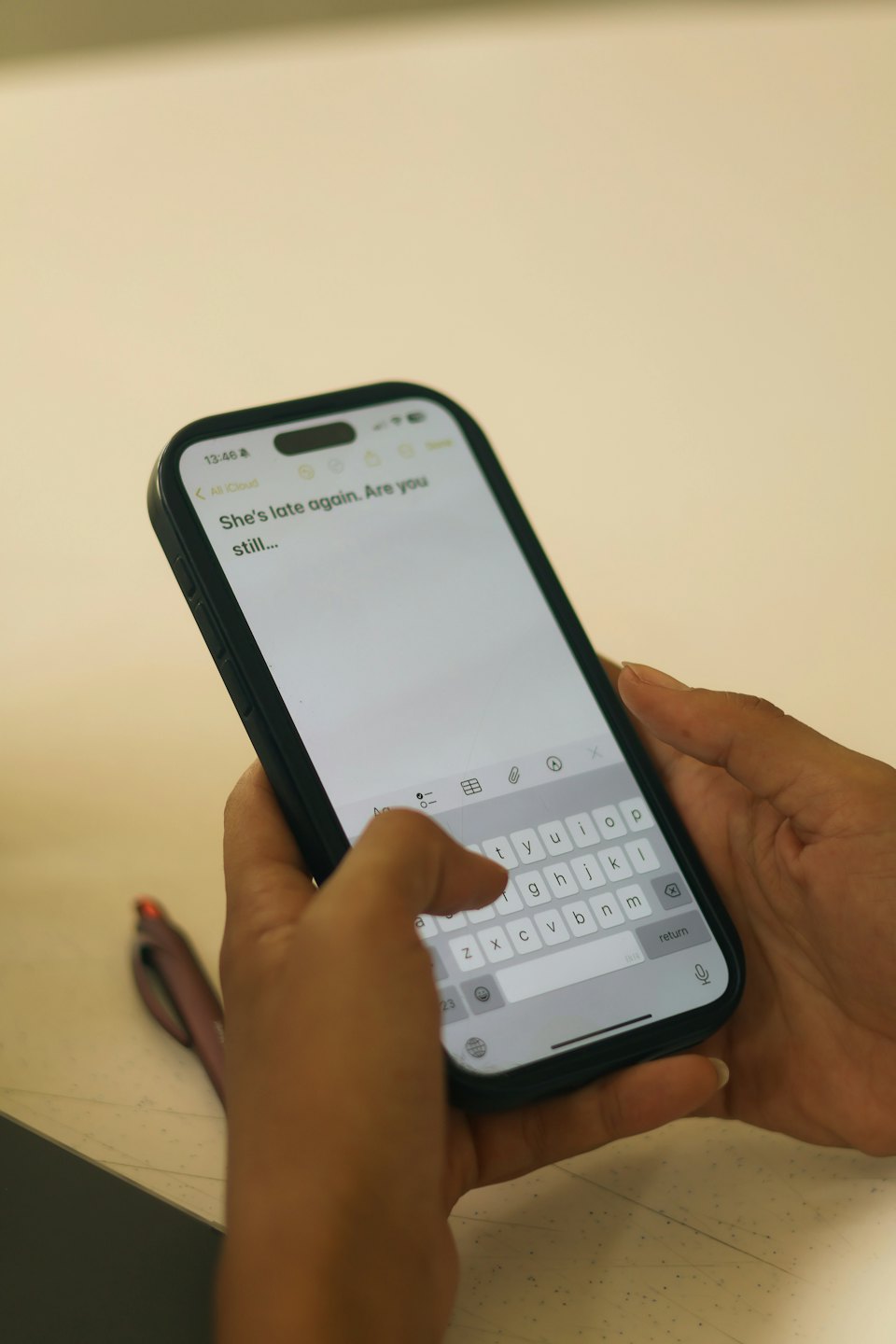 Hands typing on a smartphone screen with a virtual keyboard.