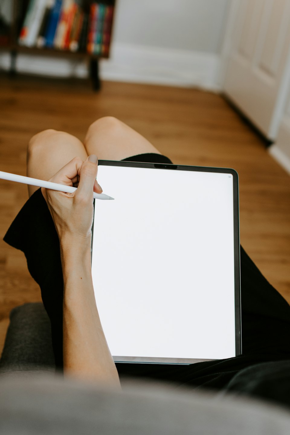 Person using a stylus on a digital tablet on their lap.